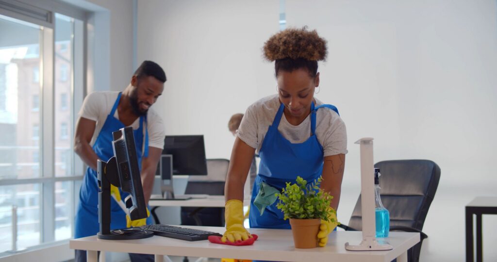 Cleaning professional wiping pollen from office desk and cleaning office floor to reduce allergens.