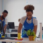 Cleaning professional wiping pollen from office desk and cleaning office floor to reduce allergens.