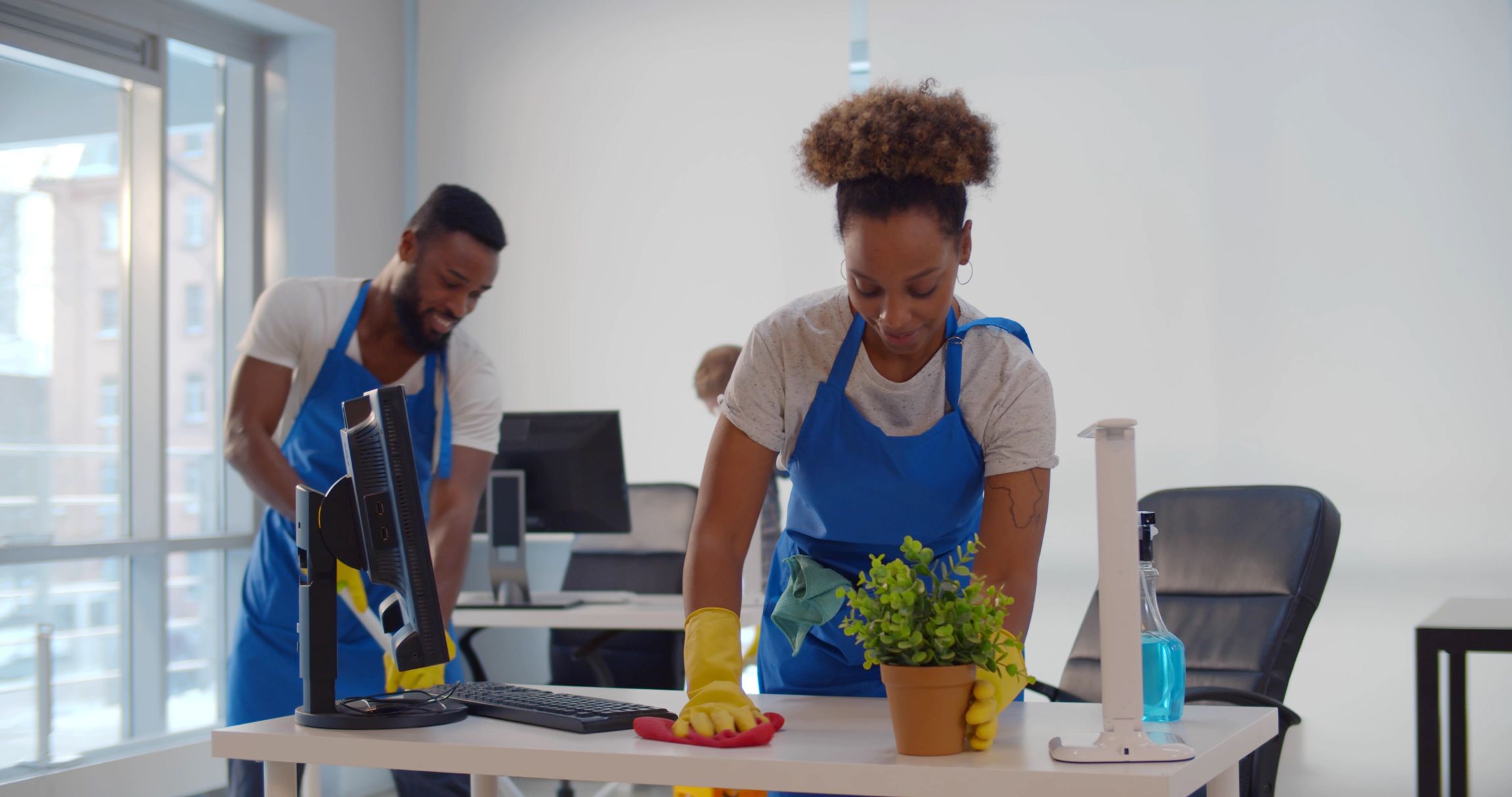 Cleaning professional wiping pollen from office desk and cleaning office floor to reduce allergens.