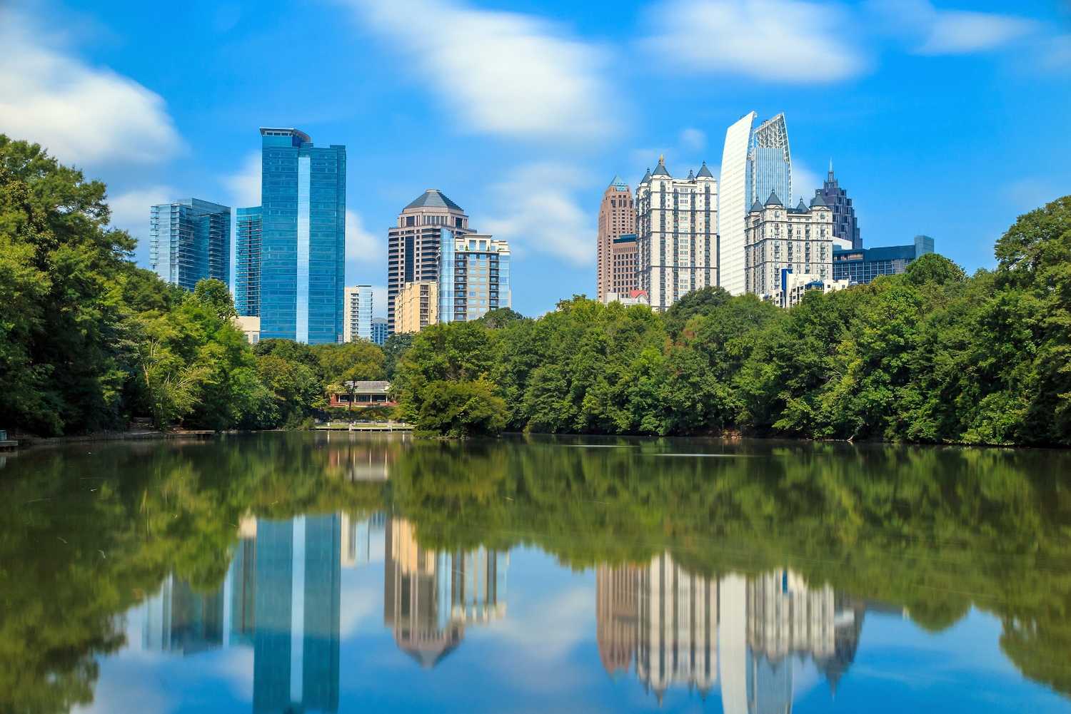 Atlanta skyline showing businesses across a lake surrounded by trees.