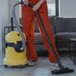 Professional cleaner vacuuming hard floors in a modern home with commercial cleaning equipment.