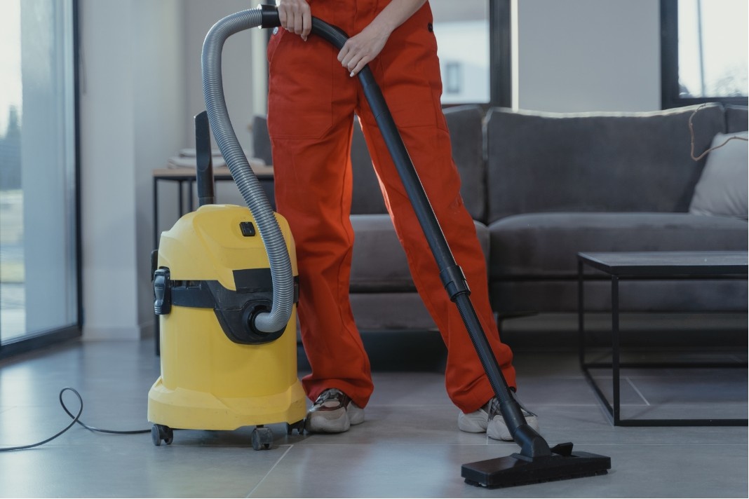 Professional cleaner vacuuming hard floors in a modern home with commercial cleaning equipment.