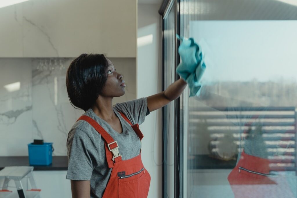 Professional cleaner wiping a large glass window with a microfiber cloth for a streak-free finish.